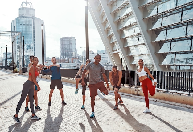 Full length of people in sports clothing warming up and stretching while exercising outdoors