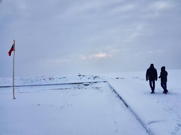 Foto lunghezza completa di persone che camminano su un paesaggio coperto di neve