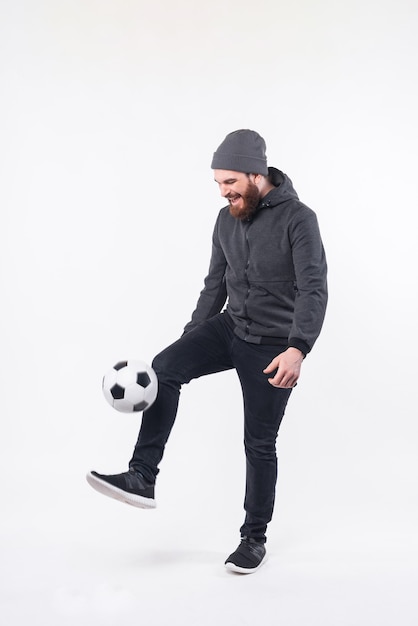 Full length photo of bearded hipster man playing with soccer ball