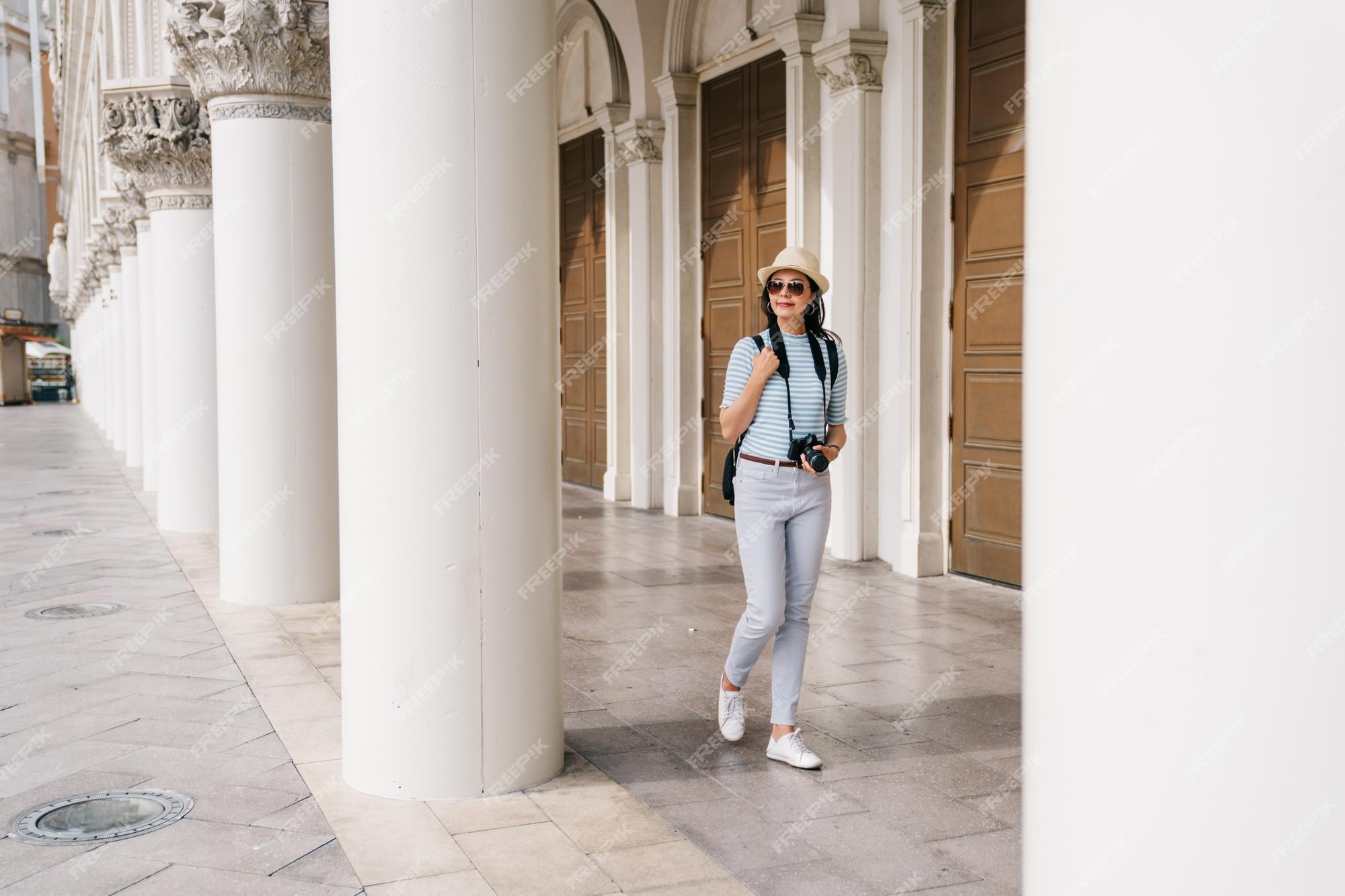 Premium Photo  Full length photo of a beautiful lady walking in the  corridor of the greek style building. asian tourist visit famous monument in  city center in las vegas. young gril