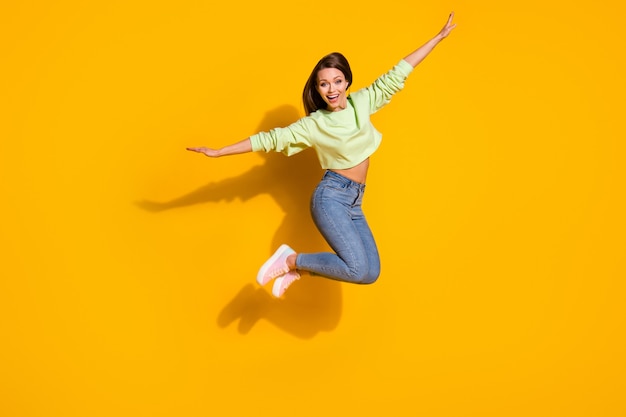 Full length photo of careless energetic girl jump hold hand enjoy fly