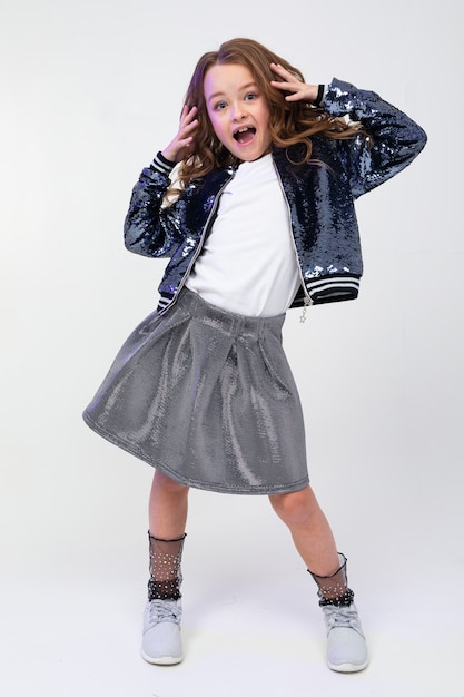 Full length photo of a cheerful girl showing emotions of joy on a white studio wall