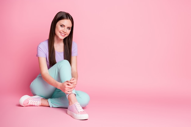 Full length photo of content nice girl sit floor copyspace enjoy weekend rest relax wear good look clothes isolated over pink color background