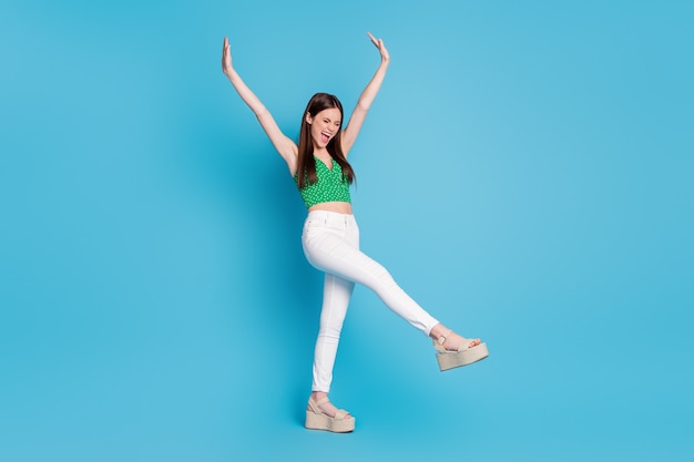 Full length photo of crazy candid girl scream raise hands enjoy free time holiday wear good look clothes isolated over blue color background