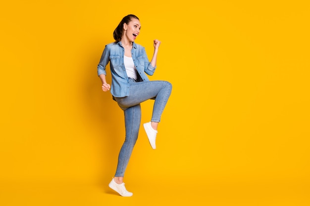 Full length photo of ecstatic girl look good copyspace enjoy rejoice lucky lottery win raise fists scream yeah isolated over shine color background