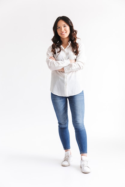 Full length photo of happy asian woman with long dark hair with beautiful smile and arms crossed