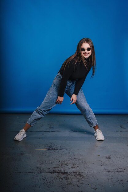 Full length photo of lovely young lady wearing casual outfit smiling and dancing isolated on blue color background