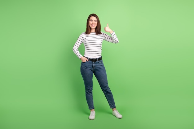 写真 若い魅力的な女性の完全な長さの写真は、緑色の背景の上に分離された親指を立てる素晴らしい理想的な広告を示しています。