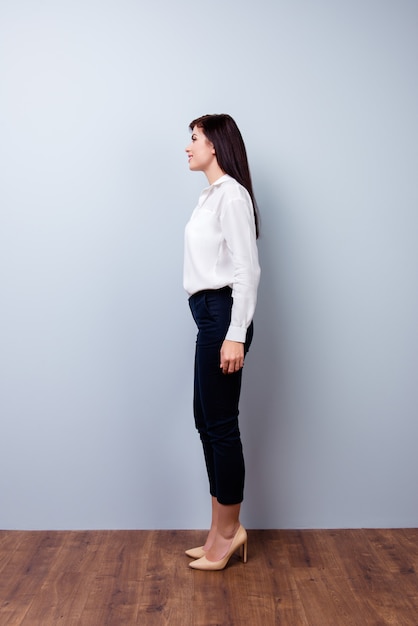 Full-length photo of side view of young confident businesswoman on gray space