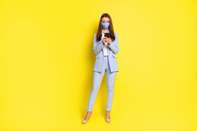 Full length photo smm worker girl respiratory mask use smartphone texting typing covid news post wear blue blazer jacket pants trousers high-heels isolated bright shine color background