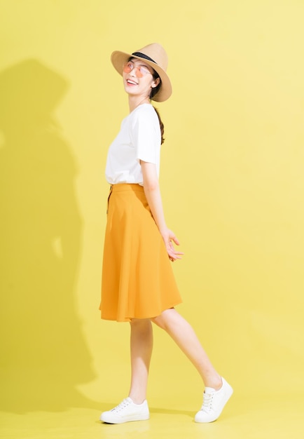 Full length photo of young Asian girl on yellow background