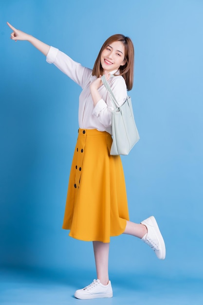 Full length photo of young Asian woman on blue background