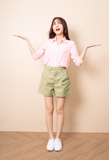 Full length photo of young Asian woman standing on background