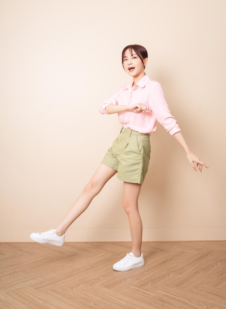 Full length photo of young Asian woman standing on background