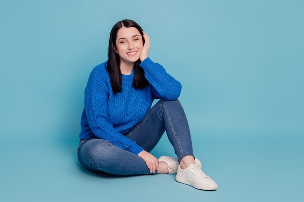 Full length photo of young attractive lovely pretty girl sitting on floor dream isolated over blue color background