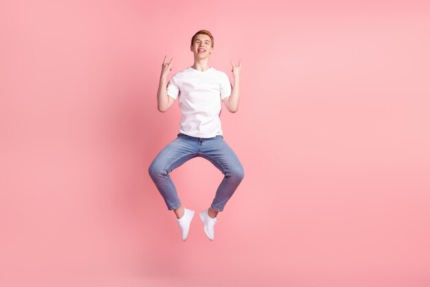 Full length photo of young excited man rejoice victory success
fists hands jump isolated over pink color background