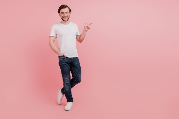 Foto a figura intera di un giovane ragazzo felice che mostra un dito copia spazio vuoto spazio vuoto annuncio pubblicitario isolato su sfondo di colore rosa