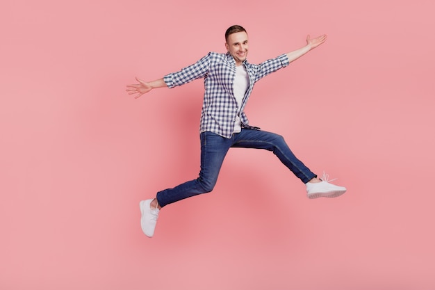 Full length photo of young guy happy positive smile jumping have fun isolated on pink color background