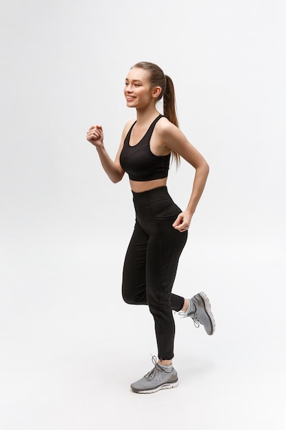 Full length picture of a sports woman running in studio  