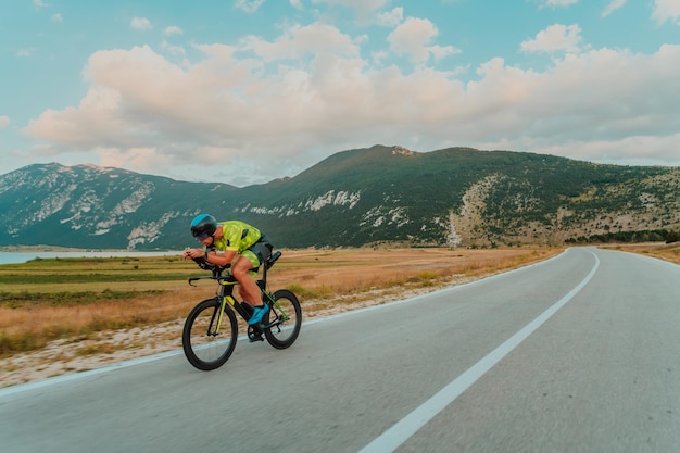 Портрет активного триатлониста в спортивной одежде и защитном шлеме в полный рост, едущего на велосипеде. Селективный фокус.