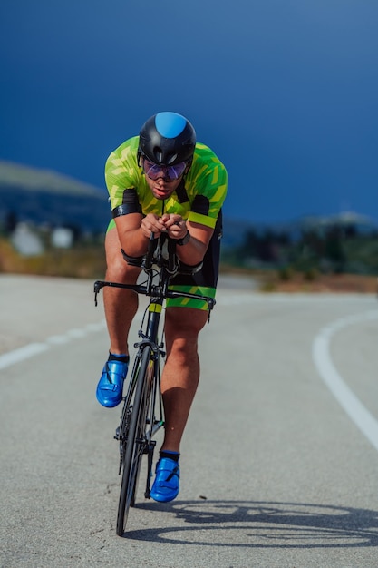 Foto ritratto a figura intera di un triatleta attivo in abbigliamento sportivo e con un casco protettivo in bicicletta. messa a fuoco selettiva.