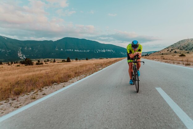 Full length portrait of an active triathlete in sportswear and with a protective helmet riding a bicycle. Selective focus.