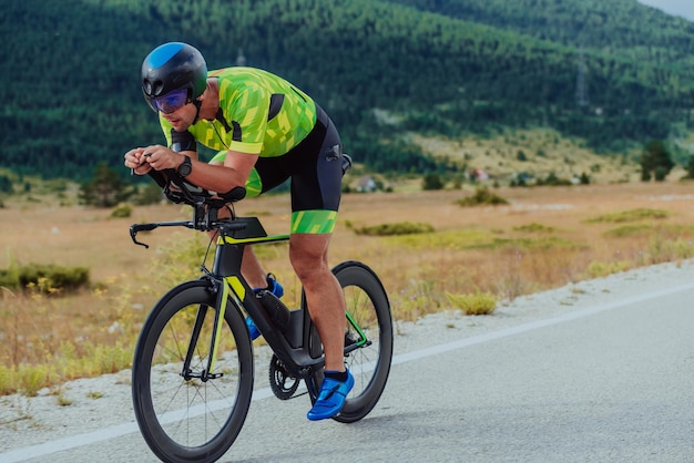 Full length portrait of an active triathlete in sportswear and with a protective helmet riding a bicycle. Selective focus.