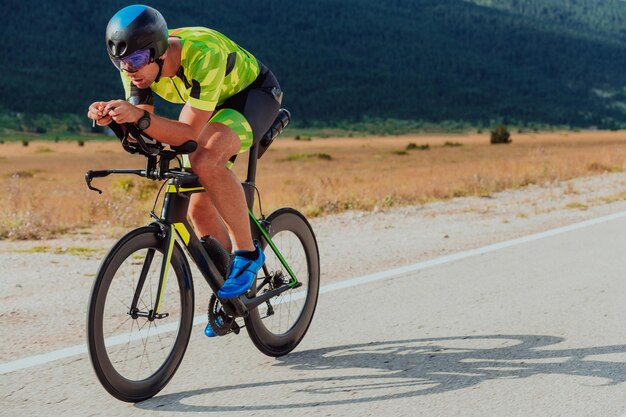 Full length portrait of an active triathlete in sportswear and with a protective helmet riding a bicycle. Selective focus.