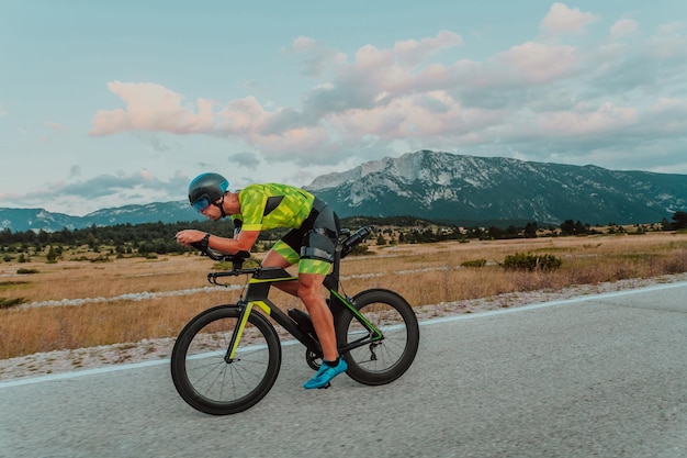 Full length portrait of an active triathlete in sportswear and with a protective helmet riding a bicycle. Selective focus.