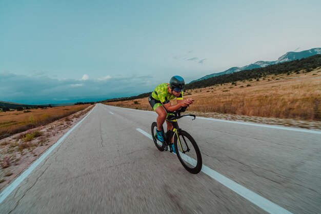 Full length portrait of an active triathlete in sportswear and with a protective helmet riding a bicycle. Selective focus.