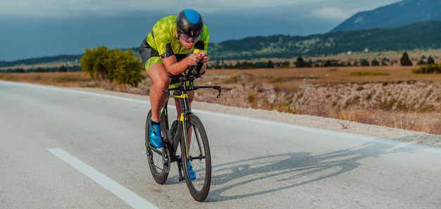 Портрет активного триатлониста в спортивной одежде и защитном шлеме в полный рост, едущего на велосипеде. Селективный фокус.