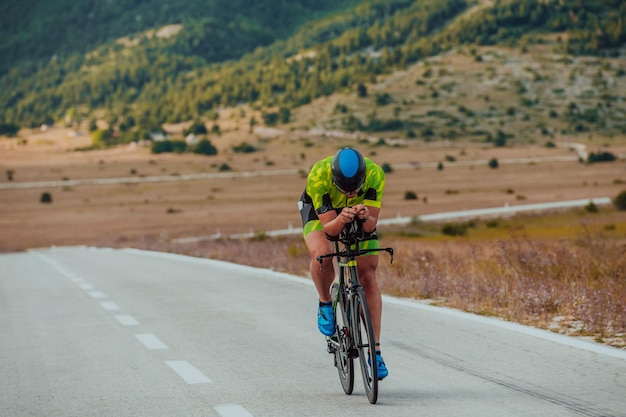 Full length portrait of an active triathlete in sportswear and with a protective helmet riding a bicycle. Selective focus.