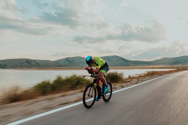 Full length portrait of an active triathlete in sportswear and with a protective helmet riding a bicycle. Selective focus.