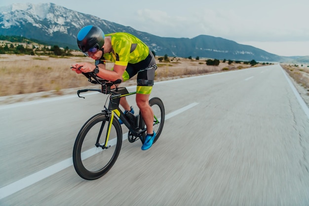 Full length portrait of an active triathlete in sportswear and with a protective helmet riding a bicycle. Selective focus.