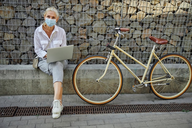 Full length portrait of adult attractive female in white blouse with retro bicycle near the stone wall in the city