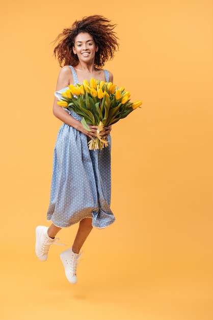 Full-length portrait of  African woman jumping with bouquet  flowers