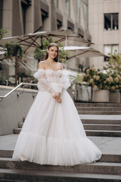 Full length portrait of beautiful bride in a white gorgeous wedding dress Fashionable wedding dress with cleavage wide long sleeves decorated with lace and beads