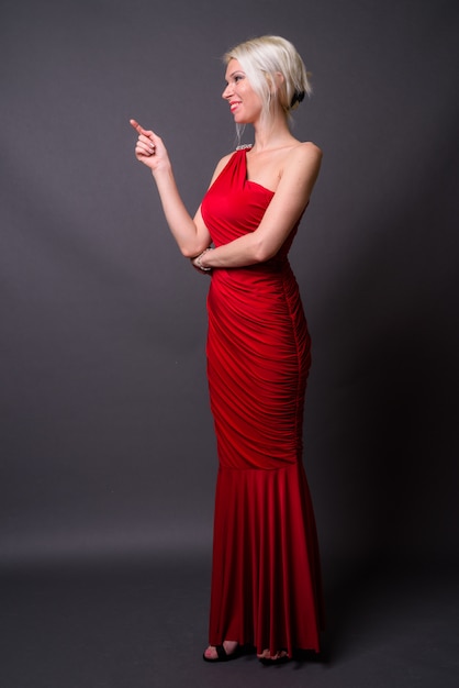 Full length portrait of beautiful woman with blond hair wearing red dress