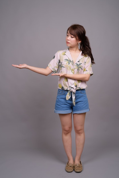 Full length portrait of beautiful young Asian woman standing