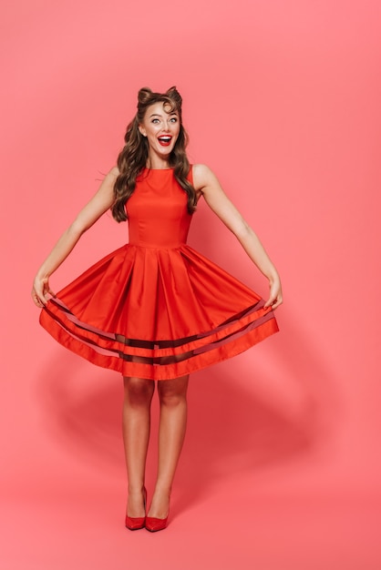 Full length portrait of a beautiful young pin-up girl wearing dress standing isolated, posing