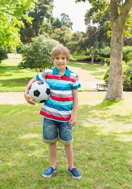 Full length portrait of a boy with ball at park