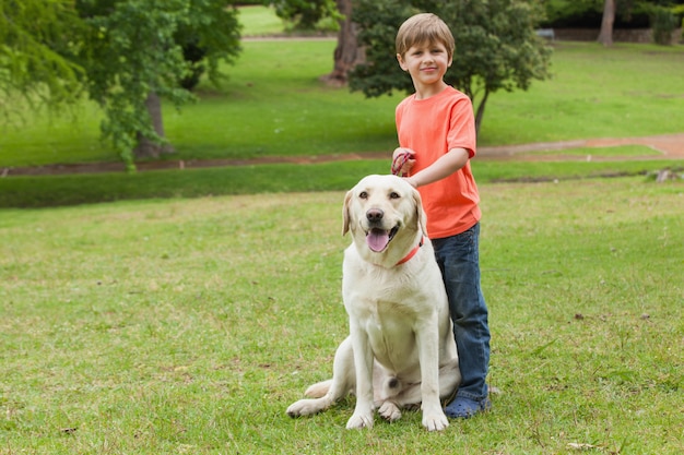 公園でペットの犬と少年の全身の肖像画