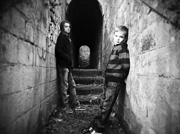 Full length portrait of boys standing against wall