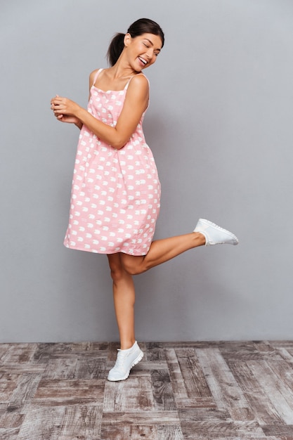 Photo full length portrait of a cheerful woman celebrating her success isolated on a gray wall