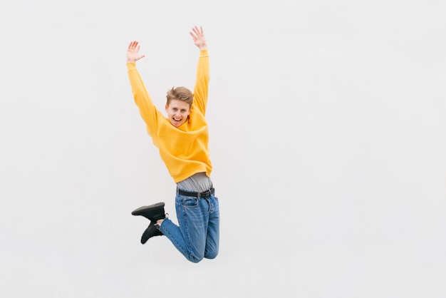 Photo full length portrait of a cheerful young man in white t-shirt pointing fingers away