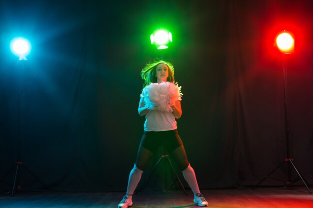 Full length portrait of cheerleader dancing with pom-poms