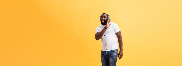 Photo full length portrait of a cherry young african american man listening to music with headphones and d