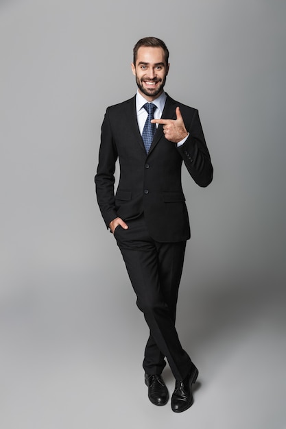 Full length portrait of a confident handsome businessman wearing suit isolated