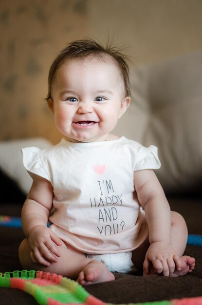 Photo full length portrait of cute baby girl sitting on bed at home