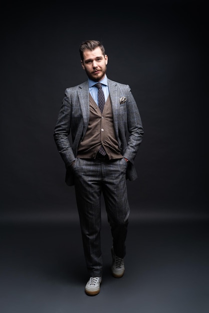 Full length portrait of a fashion male model over black background. Looking at camera.